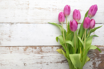 Bouquet of purple tulips on white wooden background. Top view