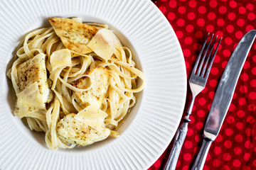 Hearty and delicious dinner, Italian spaghetti with fried chicken, cheese, spices and fresh baguette on a dark wooden background 