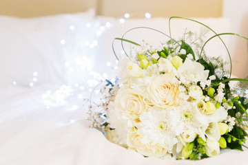 white fresh roses, freesia and mum flowers bouquet on bed, hygge style