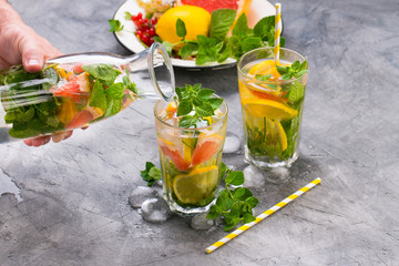 Cold refreshing summer lemonade in a glass on a grey concrete or stone background.