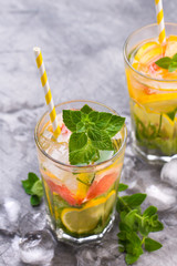 Cold refreshing summer lemonade in a glass on a grey concrete or stone background.