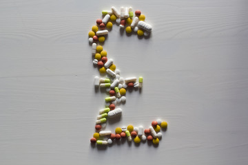 Pills in shape of British Pound money sign symbol 