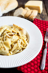 Hearty and delicious dinner, Italian spaghetti with fried chicken, cheese, spices and fresh baguette on a dark wooden background 