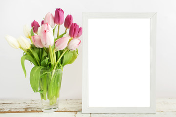 Tulip with blank picture frame on white wooden table