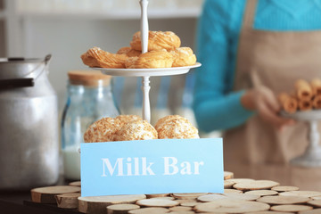 Tasty desserts and card with text MILK BAR on table