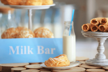 Tasty desserts and card with text MILK BAR on table
