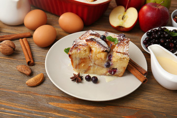 Plate with piece of baked bread pudding  on wooden table