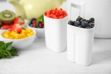 Cups with tasty homemade yogurt and berries on light wooden table