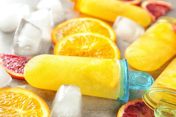 Tasty popsicles with ice cubes and citrus slices, closeup