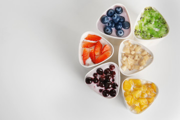 Bowls from automatic yogurt maker with fruits on white background