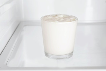 Glass with yogurt standing in fridge