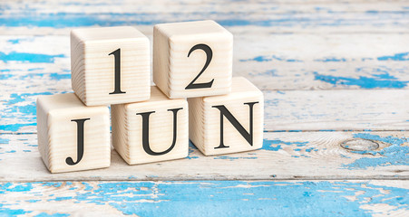 June 12th. Wooden cubes with date of 12 June on old blue wooden background.