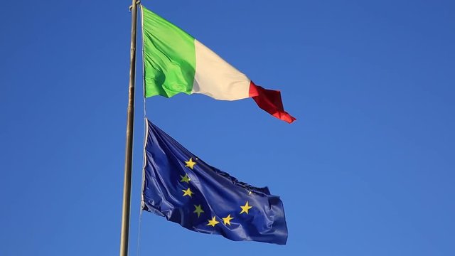 Flags of Italy and Europe waving in the blue sky background. Concept for financial treated, unique currency and financial bond