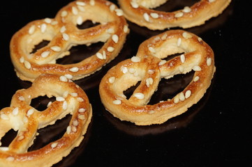 Sweet pretzel with sesame seeds isolated on black background