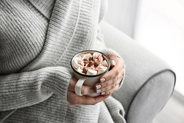 Woman holding cup of tasty cocoa with marshmallow, closeup