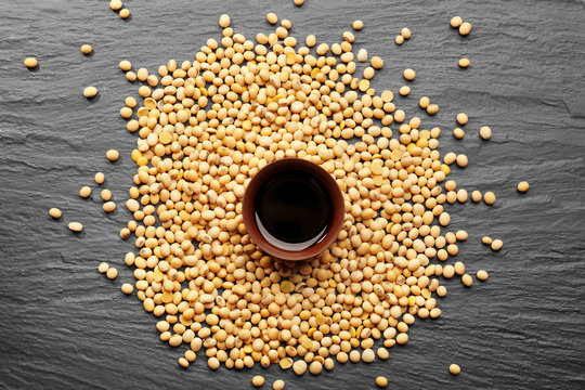 Bowl with tasty soy sauce and beans on dark textured background