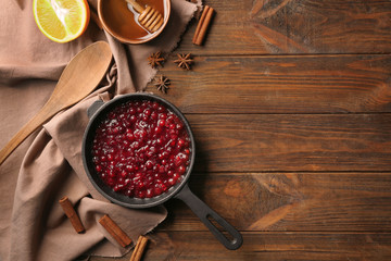 Delicious cranberry sauce in pan on wooden background