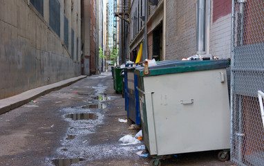 Dirty filthy back alley with dumpsters, old trash, awful puddles filled with a brine of garbage leakage and toxic chemicals - 152143569