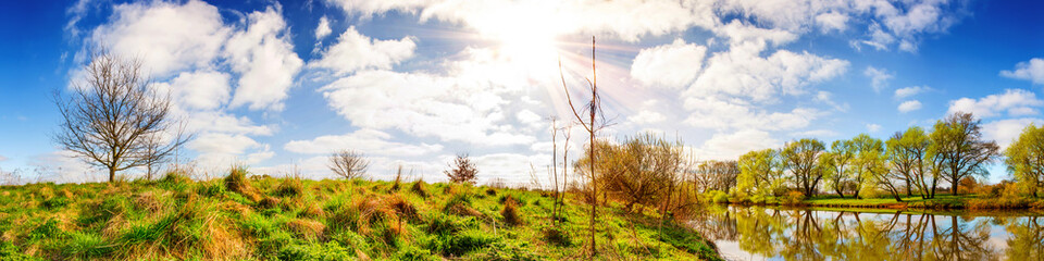 Panorama einer Landschaft mit Sonne, Fluss und Wiesen