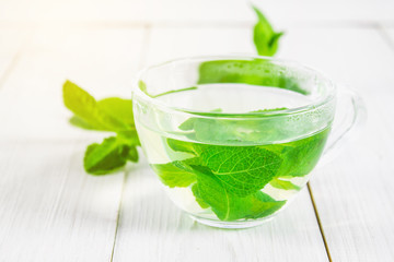 Mint tea in a cup on a white wooden table.