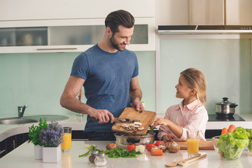 Young father and daughter cooking meal together 