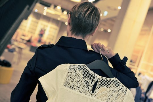 Junge Frau beim Shopping in einem Modehaus, mit Oberteil &uuml;ber der Schulter