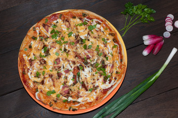 Pizza, green onion, parsley on a dark wood background, close up