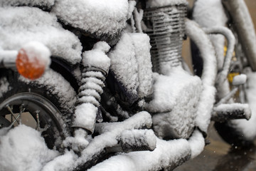 Motorcycle covered with snow. Sharp cooling, climate change. Unsuccessful time for riding a motorcycle.