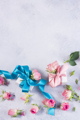 Gift boxes with blue and pink satin bows and rose flowers on gay