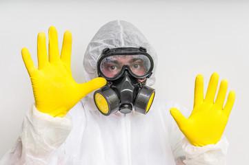 Man in coveralls with gas mask is showing stop gesture