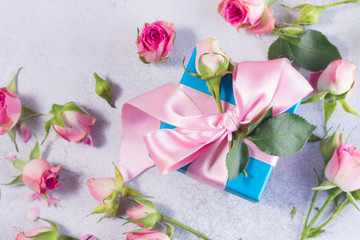 Fototapeta premium Gift blue box with pink satin bow and rose flowers close up