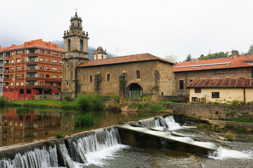 Church with river and waterfall in foreground of Balmaseda, Bizkaia, Basque Country, Spain