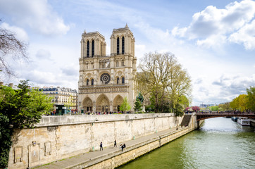 Notre Dame de Paris Cathedral on de Ile de la Cite in the beautiful European city with the Seine river flowing on the right and many tourists visiting the monument