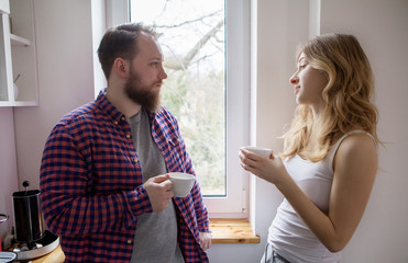 Young couple is drinking tea and coffee at home