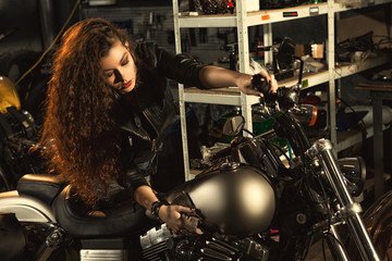 Naklejka na ściany i meble Gorgeous young woman polishing her motorbike at the workshop