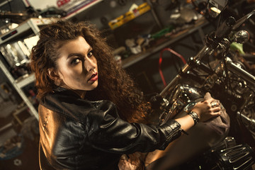 Obraz na płótnie Canvas Gorgeous young woman polishing her motorbike at the workshop