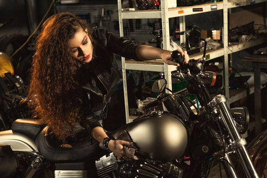 Gorgeous young woman polishing her motorbike at the workshop