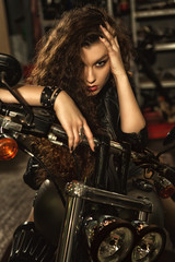 Plakat Beautiful young biker woman on her motorcycle at the workshop