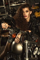 Plakat Beautiful young biker woman on her motorcycle at the workshop
