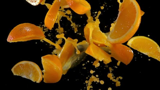 Slices of orange with juise bouncing against to the camera on a black background in slow motion
