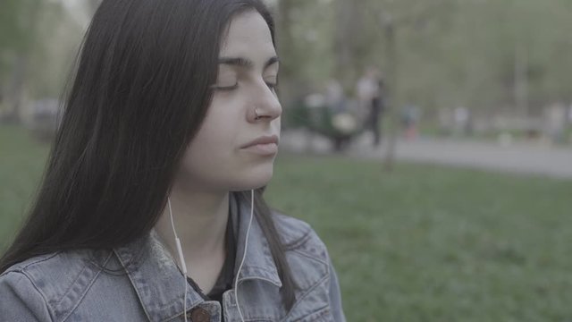 Young Woman listening music in park 4K