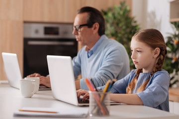 Fototapeta na wymiar Internet addicted grandfather and granddaughter using laptops indoors