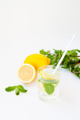 Homemade lemonade with water, lemon and mint leaves in a glass on a white background.