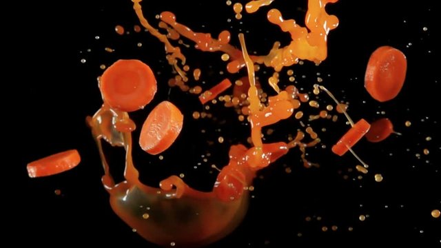 Fresh organic carrots with juise bouncing against to the camera on a black background in slow motion
