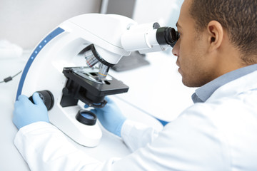 Professional male scientist working on his microscope at the lab