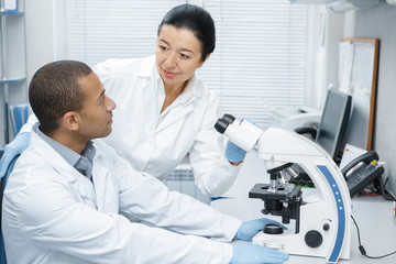 Two colleagues professional researchers using microscope at the laboratory