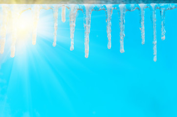 Icicles on the cornice against the blue sky