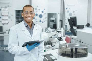 Young scientist watching laboratory machine during an experiment - obrazy, fototapety, plakaty