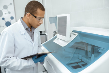 Young scientist watching laboratory machine during an experiment