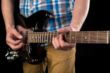 Fototapeta na wymiar Music and art. Electric guitar in the hands of a guitarist, on a black isolated background. Playing guitar. Horizontal frame